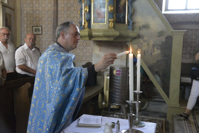 Lighting candles in church - inspiration for a Catholic home altar - Catholically
